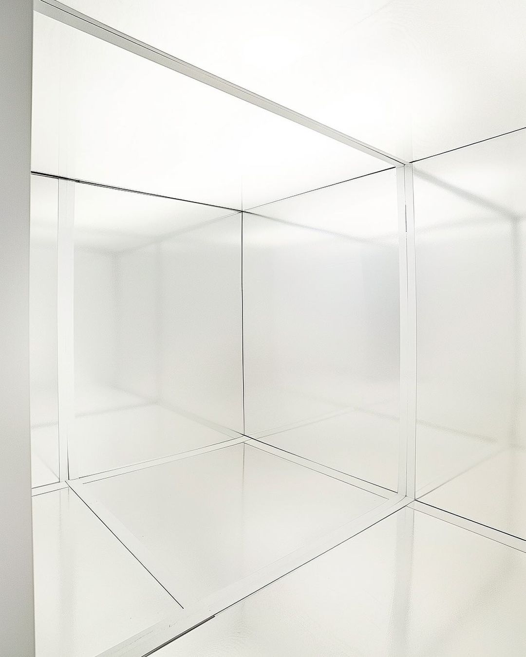 Abstract white room with mirrored surfaces and geometric lines creating a minimalist and architectural interior space.