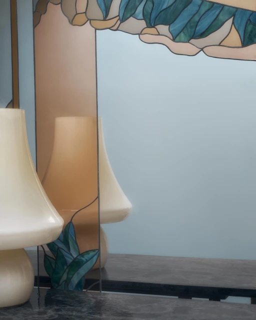 Modern interior with lamp and reflective surface featuring colorful leaf design in shades of blue, green, and tan.