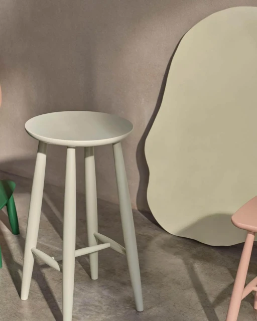 Three-legged stool in pastel light-blue color, modern minimalist design for home decor and furniture, against a neutral-toned background.