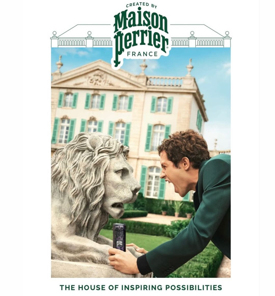 Man in suit yells at lion statue in front of mansion promoting Perrier, emphasizing architecture, brand, and humorous interaction.