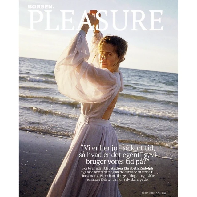 Fashion magazine cover featuring an adult woman in a white dress posing on a beach with waves.  Borsen Pleasure magazine cover.