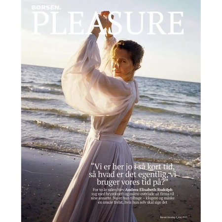 Fashion magazine cover featuring an adult woman in a white dress posing on a beach with waves.  Borsen Pleasure magazine cover.