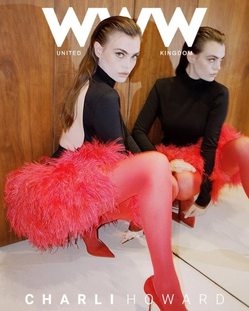 Magazine cover featuring a model in a black top, red feathered skirt, red tights, and red high heels posing with a mirrored reflection.