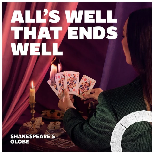 Woman in a green corduroy jacket sits at a table holding playing cards near a candle and dominoes in a dimly lit room.
