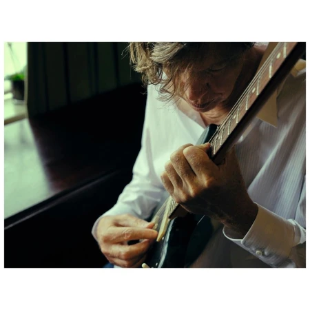 Close-up portrait of a musician playing an electric guitar, captured by Phil Fisk in London.