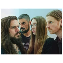 Portrait of four adults including two bearded men and a woman with long hair photographed by Phil Fisk in London.