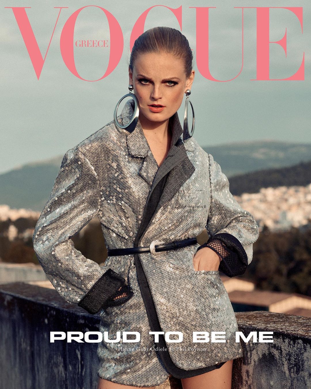 Vogue Greece cover featuring a stylish adult female model in a sequin blazer and shorts with oversized earrings, posing outdoors.
