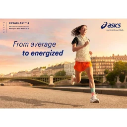 Woman running along a city riverfront at sunset, wearing orange shorts, white vest, and trainers, photographed by Philip Haynes.