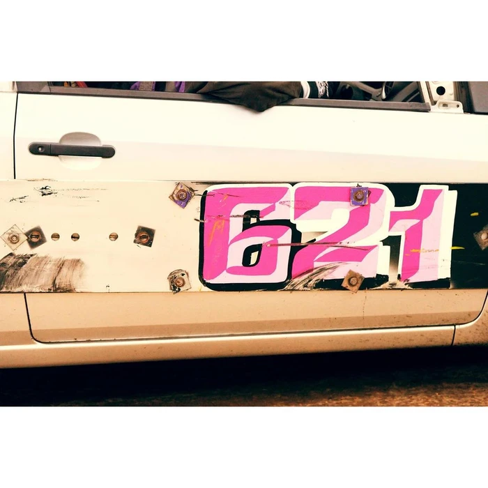 Close-up side view of a white racing car door featuring the bold pink number 621, by photographer Philip Haynes.