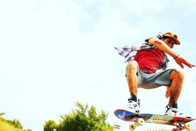 Skater mid-air performing a trick on a skateboard against a bright sky background captured by Philip North-Coombes in Los Angeles