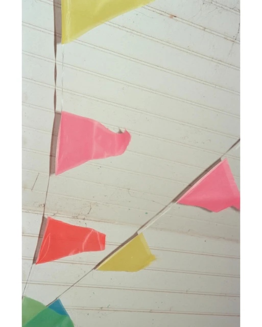 Colorful pennant banner hanging against a white wooden wall or ceiling, creating a festive and decorative atmosphere.