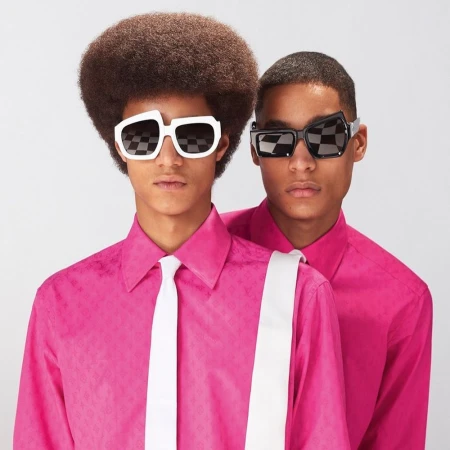 Two male models in bright pink shirts and white ties wearing avant-garde sunglasses against a plain white background