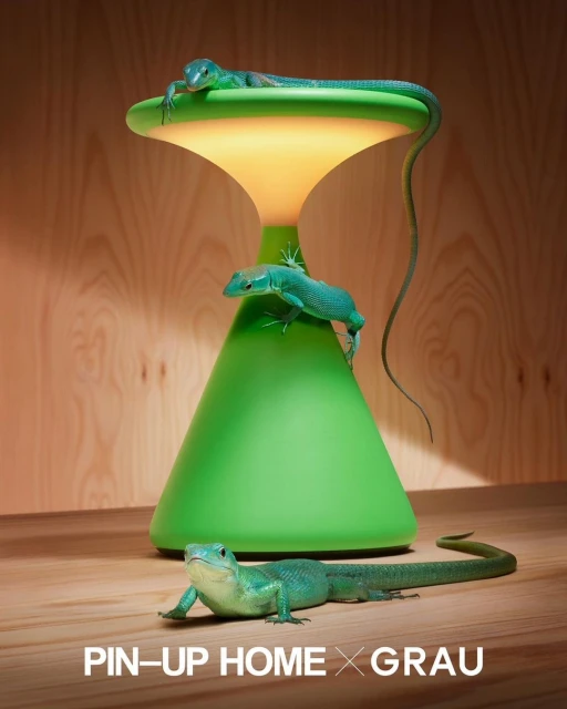Indoor product shot featuring a green, hourglass-shaped lamp with three green lizards climbing on it against a wooden background.