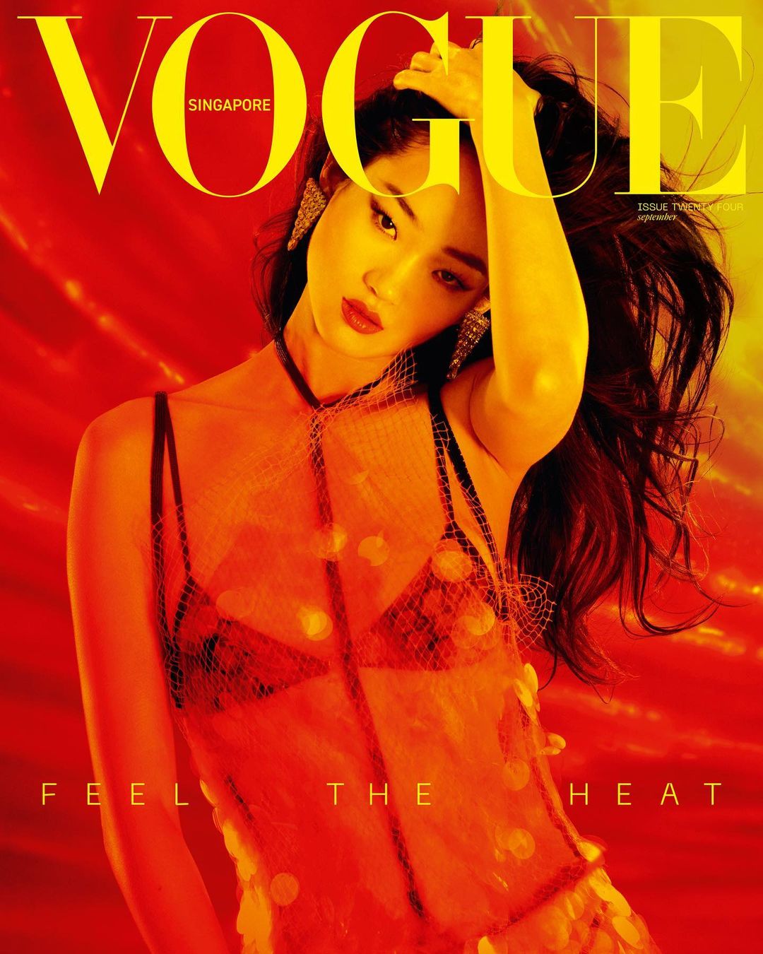 Vogue Singapore cover featuring a woman with dark hair in a sheer, orange dress, gazing at the camera against a blurred orange background.