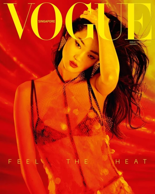 Vogue Singapore cover featuring a woman with dark hair in a sheer, orange dress, gazing at the camera against a blurred orange background.