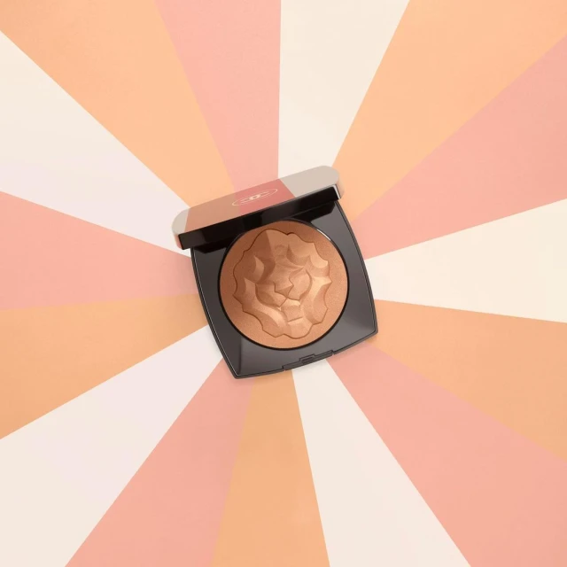 Bronzer compact with floral pattern on a background with peach and cream radial pattern, studio lighting, product shot.