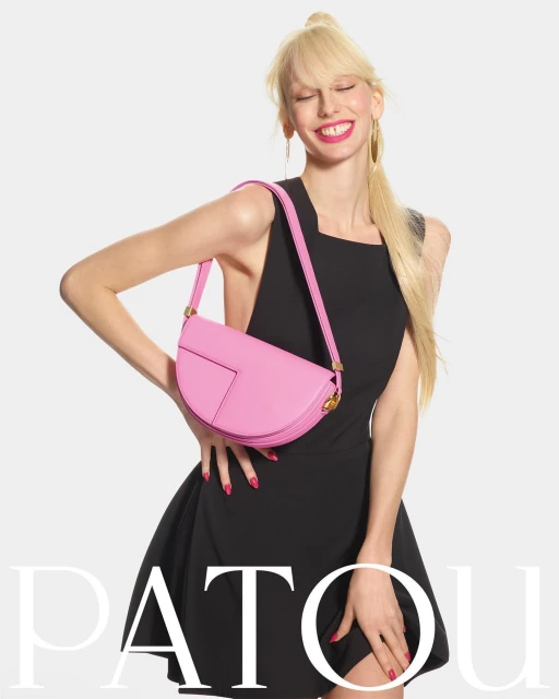 Fashionable woman wearing a black dress and a pink purse, posing in a studio with a white background. Beauty and style editorial.