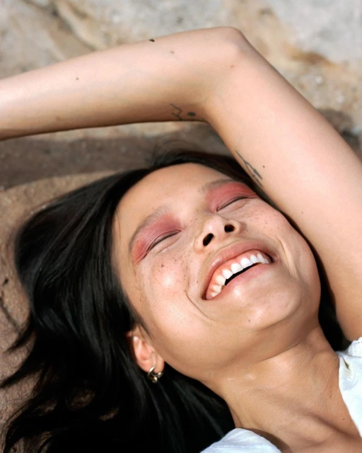 Close-up of an Asian woman with dark hair smiling widely, wearing bright pink eye shadow and silver hoop earrings, outdoors.