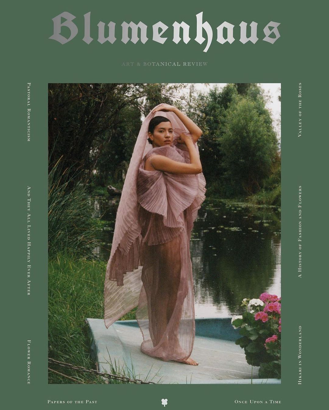 Magazine cover featuring a woman in a flowing pink dress standing in a lush, watery garden, evoking a dreamy, floral-themed atmosphere.