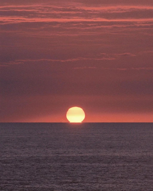 Vibrant sunset over the ocean, featuring a yellow sun near the horizon, creating a gradient sky with orange and red hues.
