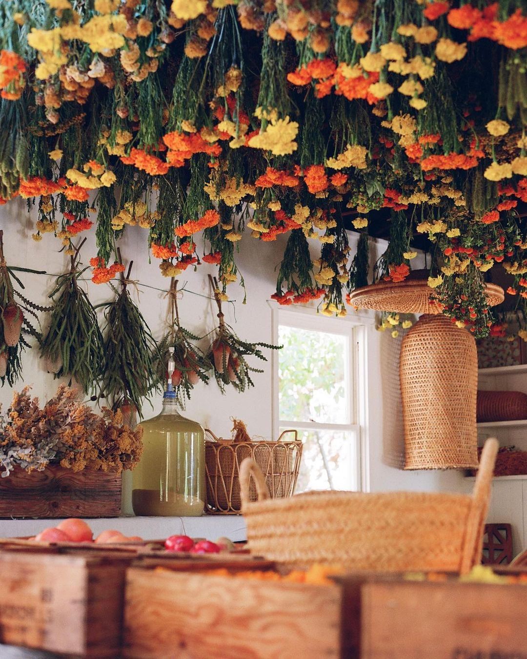 Eye-level shot of an indoor space adorned with suspended dried flowers, rustic baskets, and wooden crates filled with more dried flowers.