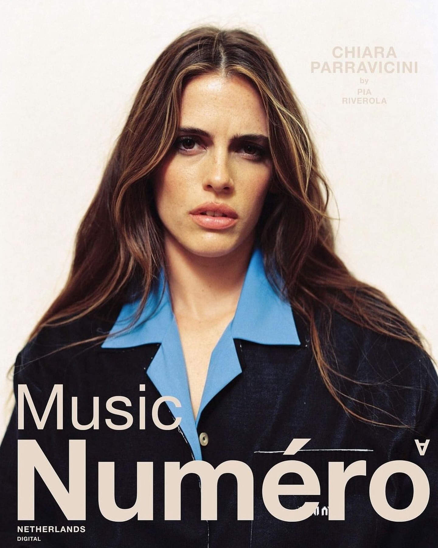Portrait of Chiara Parravicini, brunette hair and blue shirt, wearing a black jacket, with 'Numero' magazine cover in the foreground.
