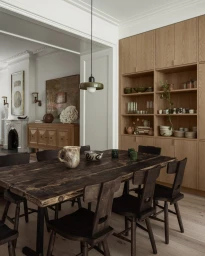 Modern dining room interior with a dark wooden dining table, black chairs, and built-in oak cabinetry in Los Angeles.