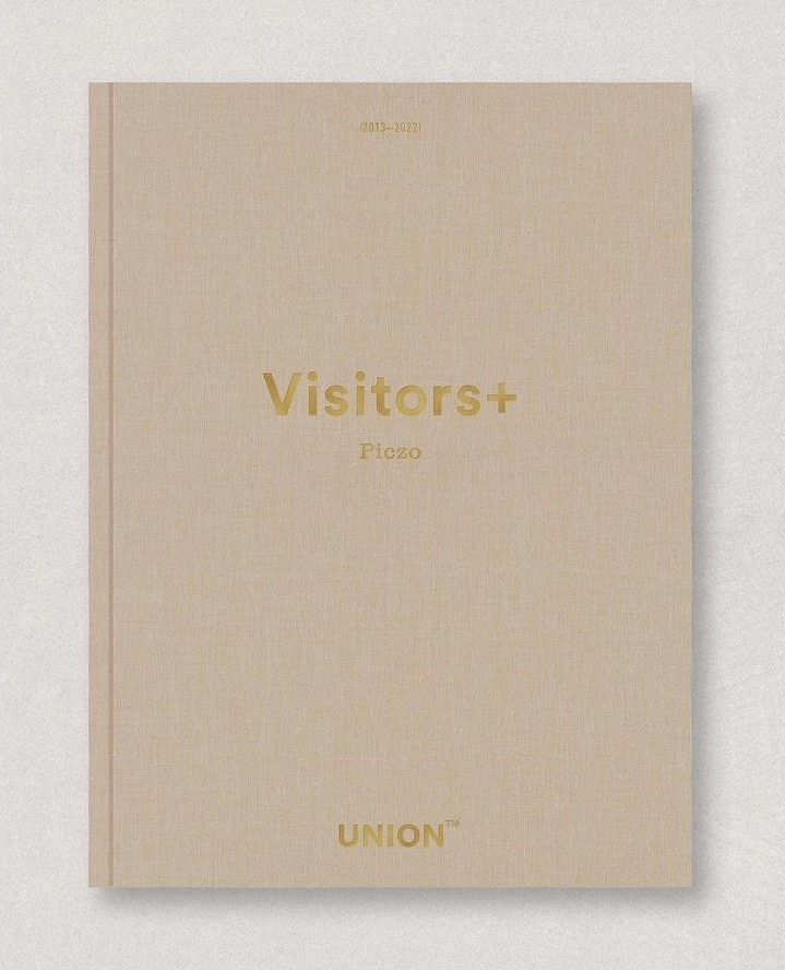 Tan hardcover book cover with 'Visitors+' and 'Union' printed in gold text. Clean studio shot on a neutral surface.