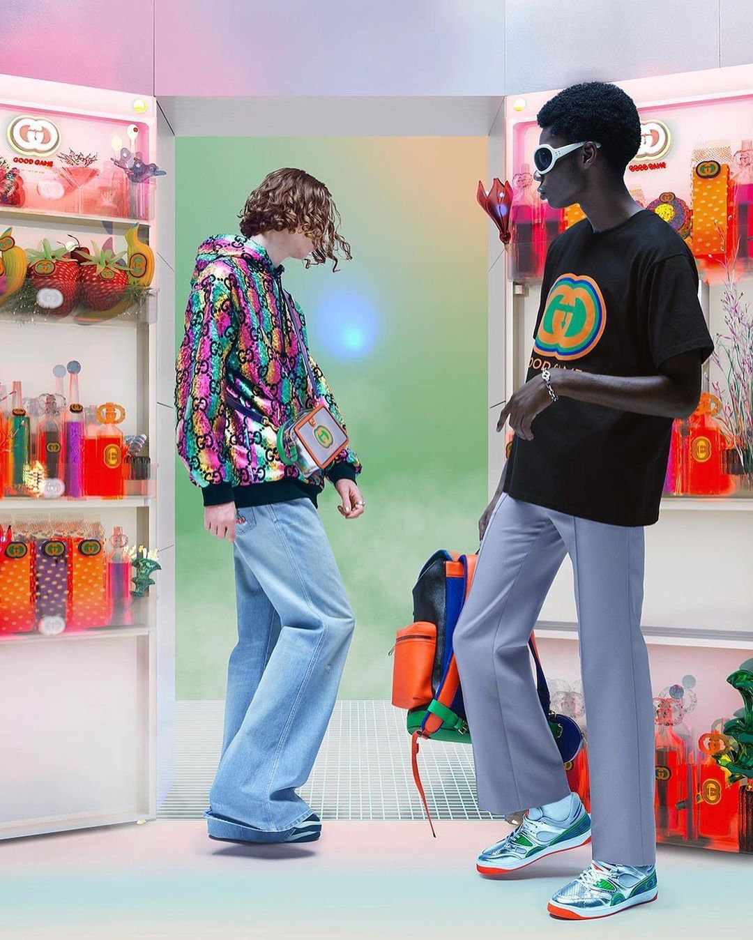 Two fashion models in Gucci apparel pose in front of shelves stocked with various colorful decorative objects and bottles of liquid.