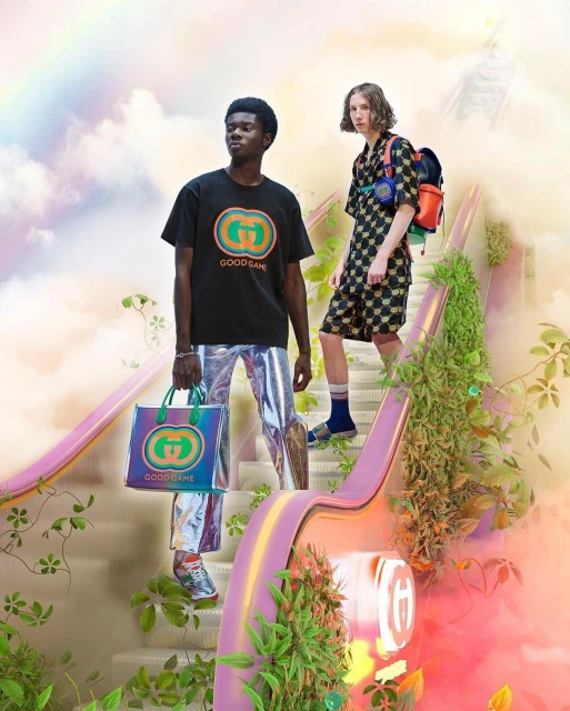 Two models pose on a pastel staircase with greenery. One carries a Gucci tote, wearing shiny pants and a Gucci logo t-shirt.
