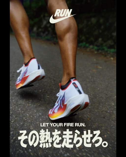 Runner's legs and feet in motion, featuring white and colorful running shoes with the Nike logo, on a gray asphalt road.