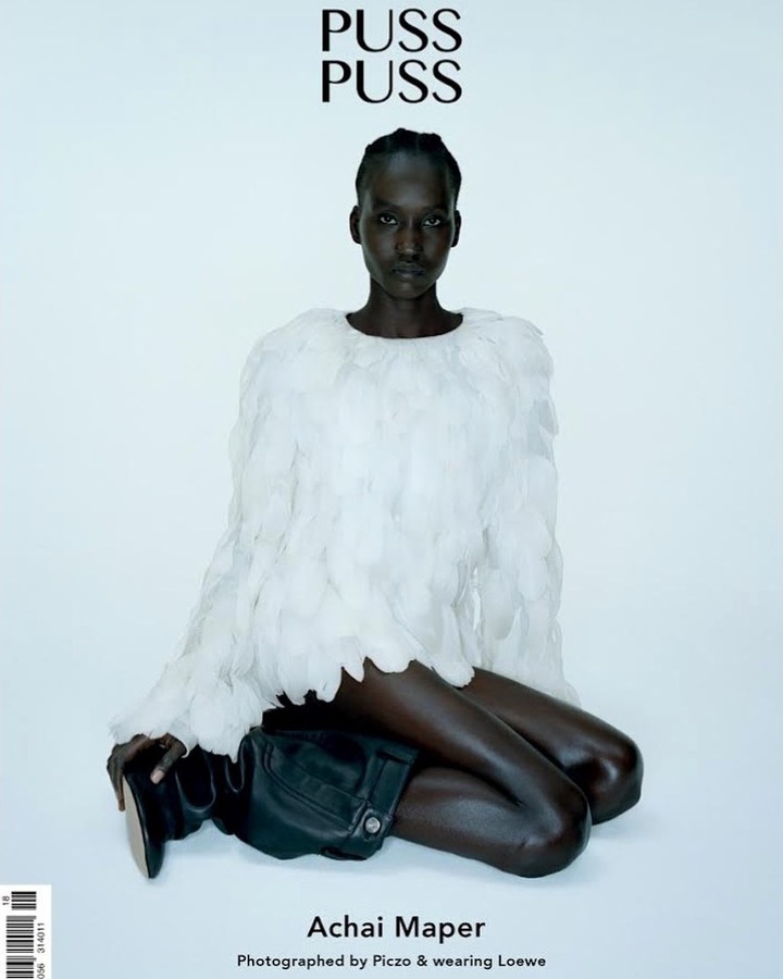 Fashion editorial shot of a dark-skinned model wearing a feather-like top and black boots against a light backdrop, magazine cover.