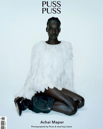Fashion editorial shot of a dark-skinned model wearing a feather-like top and black boots against a light backdrop, magazine cover.