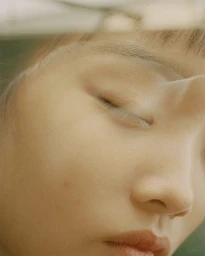 Close-up portrait of a woman with closed eyes photographed through a glass surface by Piczo
