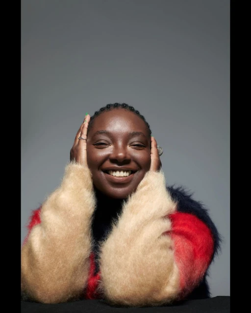 Smiling Black woman in a colourful sweater. Portrait of a cheerful African woman in fashion attire against a neutral grey background.