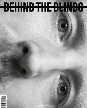Black and white close-up of a man's face, presented upside down, with a magazine title 'Behind the Blinds' overlaid.