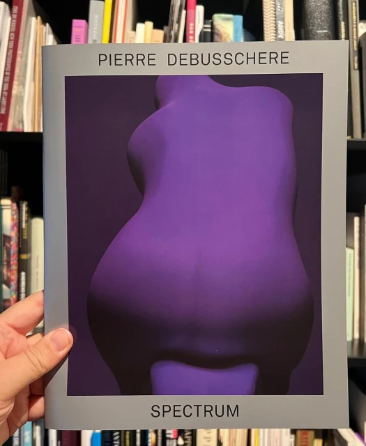 Book cover of 'Pierre Debusschere Spectrum' featuring a purple, abstract human torso sculpture against a dark purple backdrop.