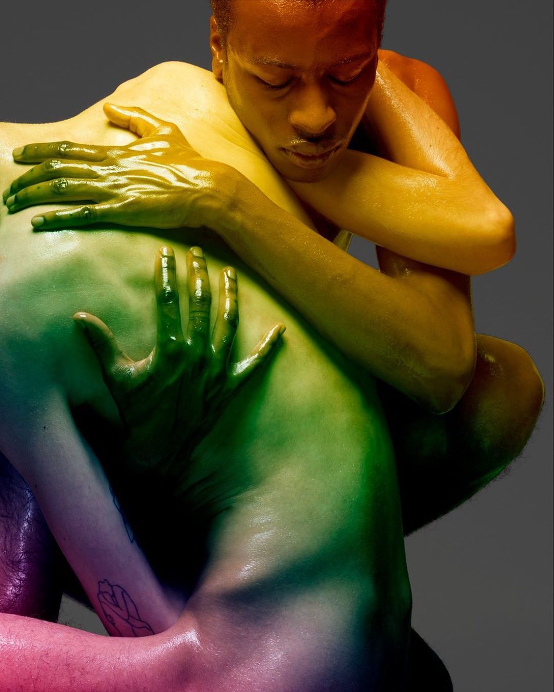 Two adults embracing, body art with rainbow colors, close-up studio shot. LGBTQ+ themes, unity, love and connection. LGBT community representation.