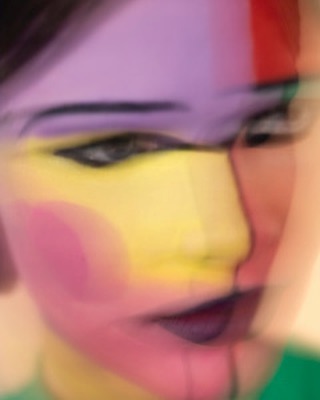 Abstract portrait of a woman with color block face paint in shades of purple, yellow, pink, and green.