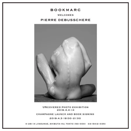 Black-and-white artistic nude portrait featuring a flexed adult male on a wooden surface, presented in a promotional poster for a photo exhibition.