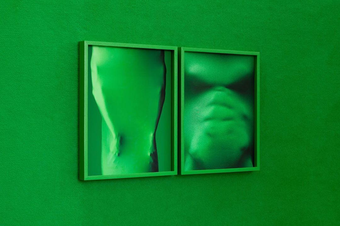 Two framed, abstract, monochromatic green portraits hang on a matching green wall, offering a minimalist and visually cohesive aesthetic.