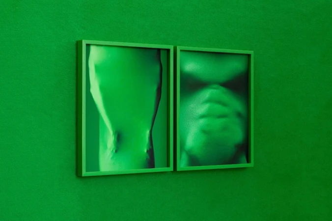 Two framed, abstract, monochromatic green portraits hang on a matching green wall, offering a minimalist and visually cohesive aesthetic.