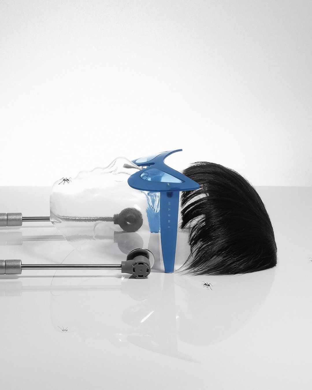 Orthodontic headgear with adjustable metal rods and a blue plastic facebow, isolated against a white backdrop in a studio setting.