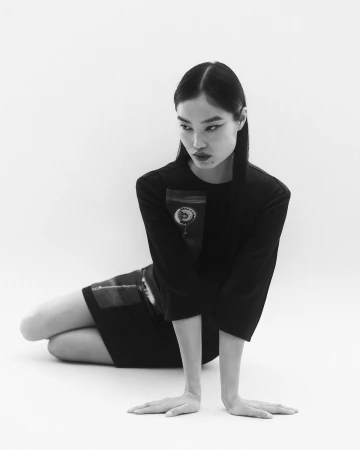 Monochrome portrait of an Asian woman in a black dress kneeling on a white seamless background photographed by Pierre Tostain.