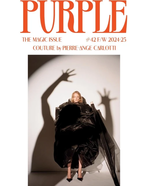 Blonde woman in a voluminous black dress poses for the cover of Purple Magazine's Magic Issue against a white backdrop with shadow art.
