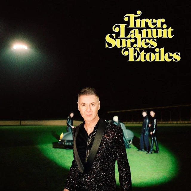 Album cover featuring a man in a sparkly blazer in the foreground, with others and cars in the background on a green-lit ground.