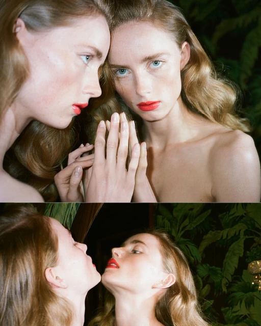 Two women, one looking at the camera, the other in profile with a mirror effect, show off bright red lipstick in a studio portrait.