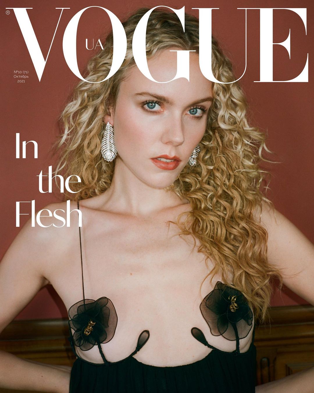 Vogue UA cover featuring a blonde woman with curly hair wearing a black dress with floral accents, against a red-brown background.