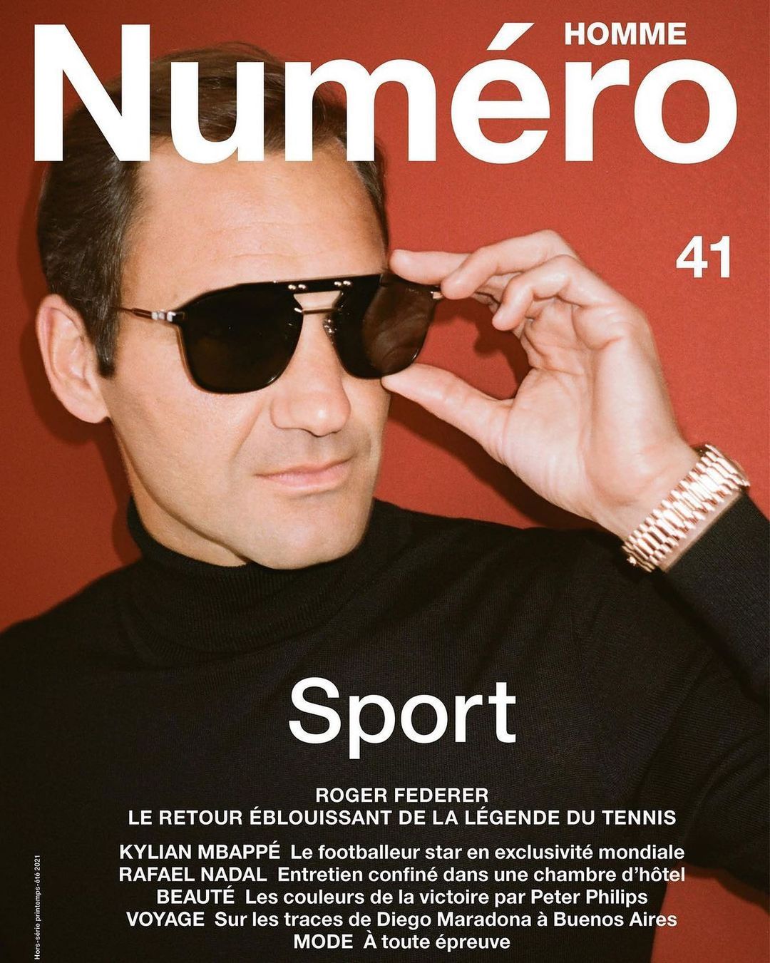 Magazine cover featuring a man in sunglasses and a black turtleneck sweater, set against a red background with bold white magazine text.