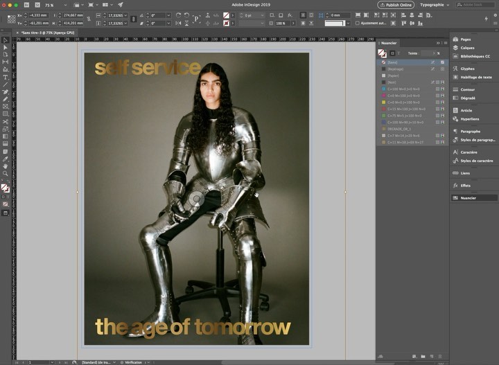 Magazine cover features a person in a silver metal suit of armour sitting on a black chair against a tan background with gold text.